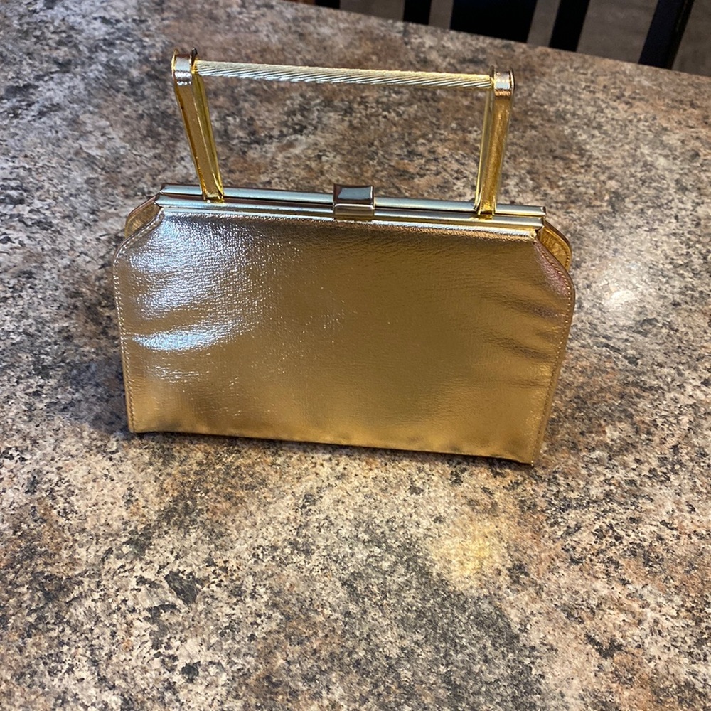 Small gold colored clutch with handle.